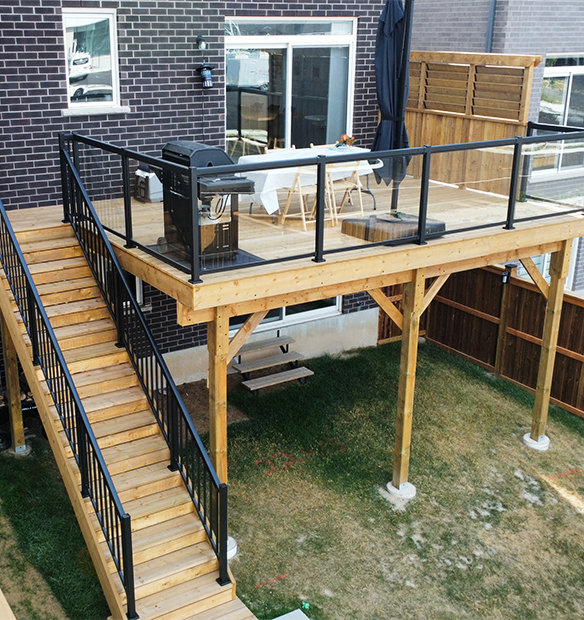 Custom residential wood deck with black aluminum, glass deck railings.